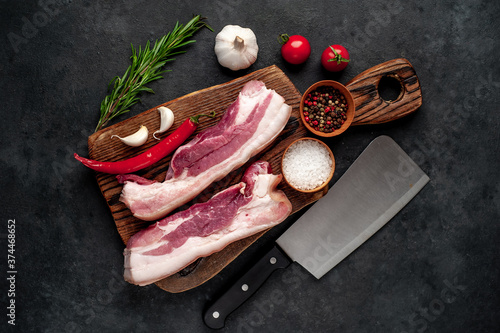 raw pork breast with spices on a cutting board on a stone background