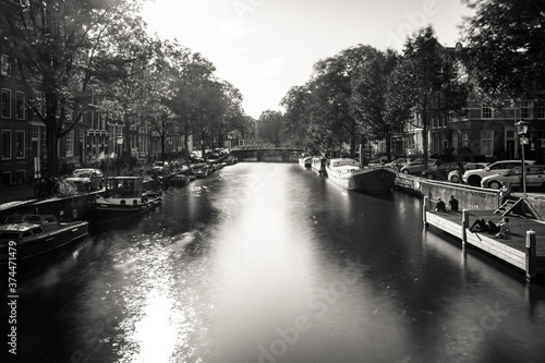 Amsterdam, Holland, the Netherlands - July 6 2020: capture of the typical Amsterdam scenery in black and white with canal, canalo house, clouds and the iconic buildings of the city