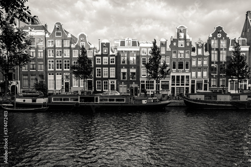 Amsterdam, Holland, the Netherlands - July 6 2020: capture of the typical Amsterdam scenery in black and white with canal, canalo house, clouds and the iconic buildings of the city