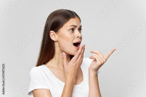  frightened girl covers her mouth with her hand and points her Finger towards Copy Space