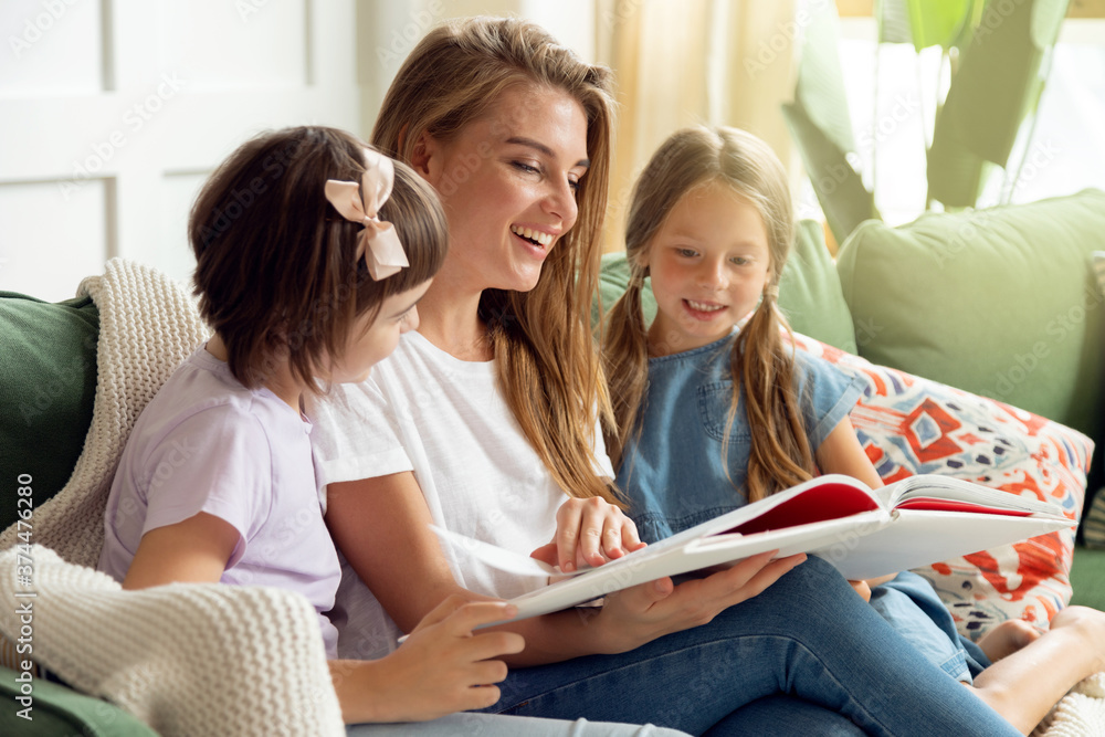 Children spend time at home with their parents reading a book on the sofa Children spend time at home with their parents reading a book on the sofa