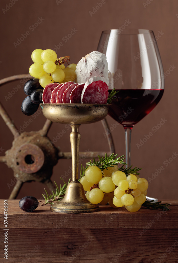 Obraz premium Glass of wine with snacks on a brown background.