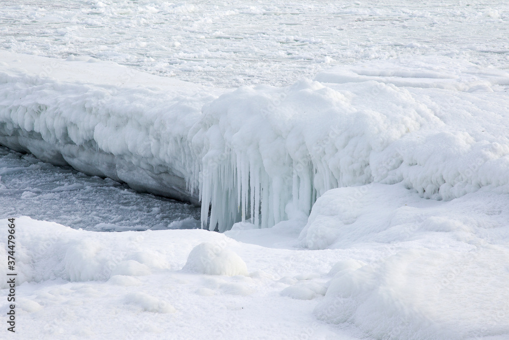 Natural sea ice blocks breaking up against the shore and ice during freezing winter weather. In the background Natural sea ice blocks breaking up against the shore and ice during freezing winter weather. In the background