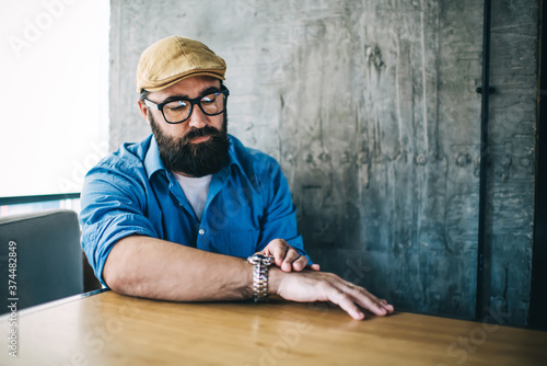 Принти на полотні Serious caucasian male in casual wear sitting in cafe interior waiting for meeti