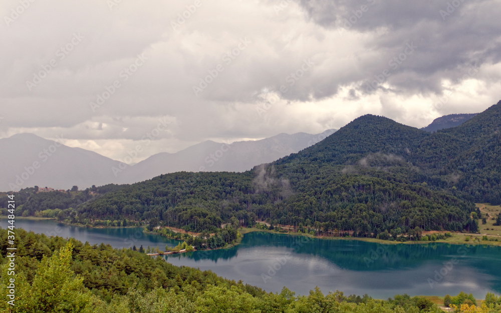 picturesque mountain lake and green forest under cloudy sky
