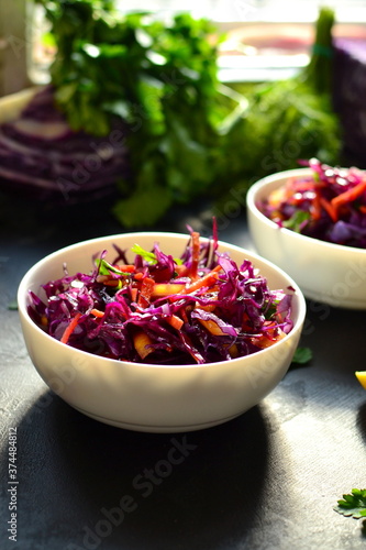 Red cabbage salad with bell peppers and carrots. Dark background. Healthy bright food.