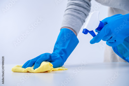 Wallpaper Mural Young woman housekeeper in apron is cleaning, wiping down table surface with blue gloves, wet yellow rag, spraying bottle cleaner, closeup design concept. Torontodigital.ca