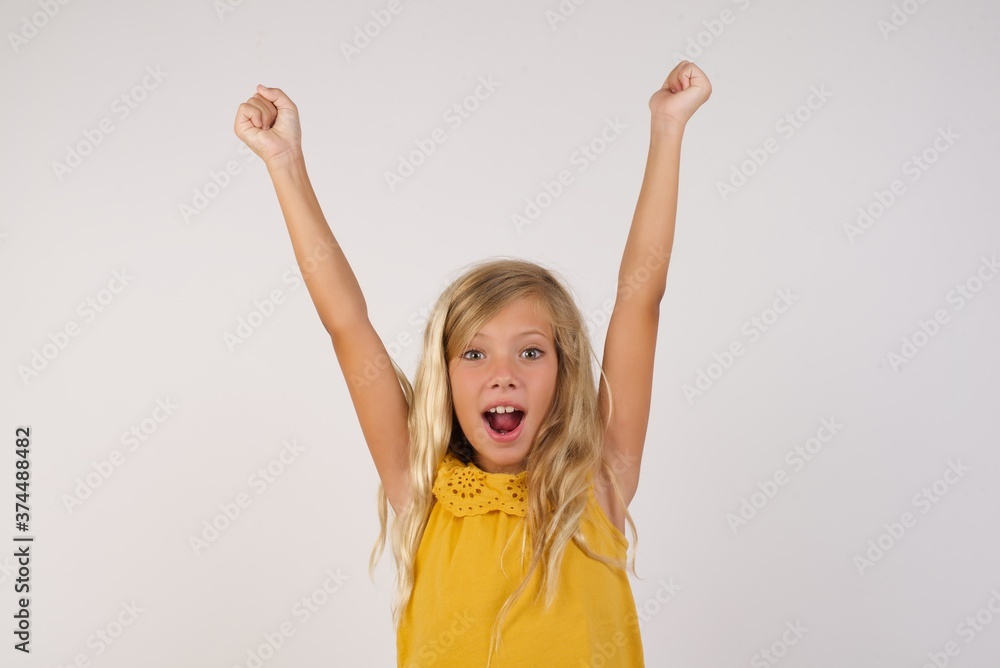 Shouting screaming beautiful Little girl with beautiful blonde hair over white background having won contests seeing sales discounted goods with hands up amazed