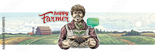 Happy farmer holds a young plant shoot in his hands, against the background of an agricultural landscape.