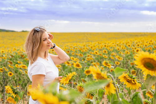 Sunflower field. A beautiful girl in a white T-shirt among many blooming sunflowers.