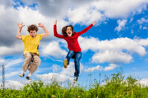 Girl and boy running  jumping against blue sky 