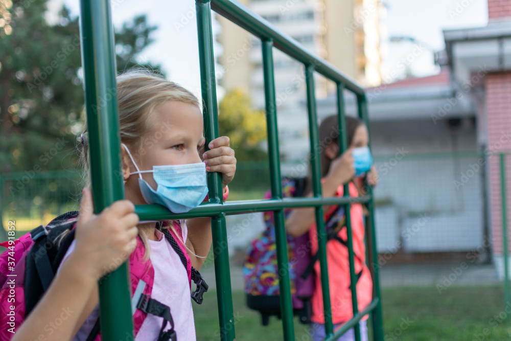 Obraz premium Social distance in school concept. Schoolchildren in protective masks show social distance of 6 feet. Back to school during coronavirus pandemic. School child wearing protective face mask in school