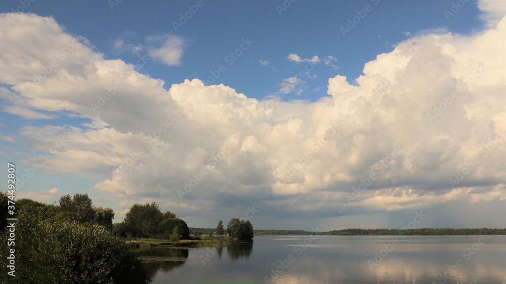 Huge white beautiful clouds over lake in summer, Russia