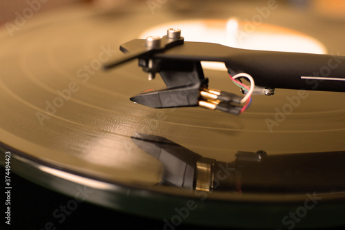 Vinyl Record Player. Close up image of cartridge and tonearm. The stylus over vinyl disc.