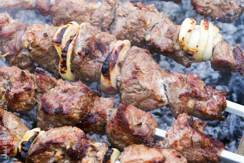 Grilled kebab cooking on metal skewer. Roasted meat cooked at barbecue. BBQ fresh beef meat chop slices. Traditional eastern dish, shish kebab. Grill on charcoal and flame, picnic, street food Grilled kebab cooking on metal skewer. Roasted meat cooked at barbecue. BBQ fresh beef meat chop slices. Traditional eastern dish, shish kebab. Grill on charcoal and flame, picnic, street food