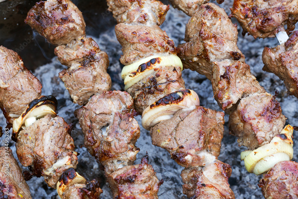 Grilled kebab cooking on metal skewer. Roasted meat cooked at barbecue. BBQ fresh beef meat chop slices. Traditional eastern dish, shish kebab. Grill on charcoal and flame, picnic, street food Grilled kebab cooking on metal skewer. Roasted meat cooked at barbecue. BBQ fresh beef meat chop slices. Traditional eastern dish, shish kebab. Grill on charcoal and flame, picnic, street food