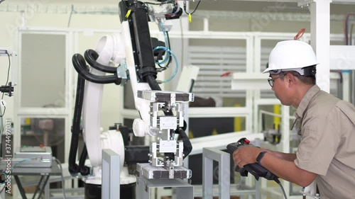 Engineer setting up automatic robot arms in smart factory, automotive industry, industrial concept.