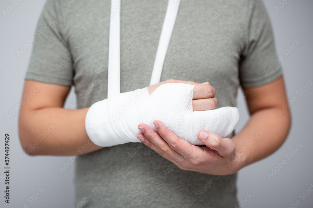 Φωτογραφία first aid concept - close up of male hand with bandage and gypsum