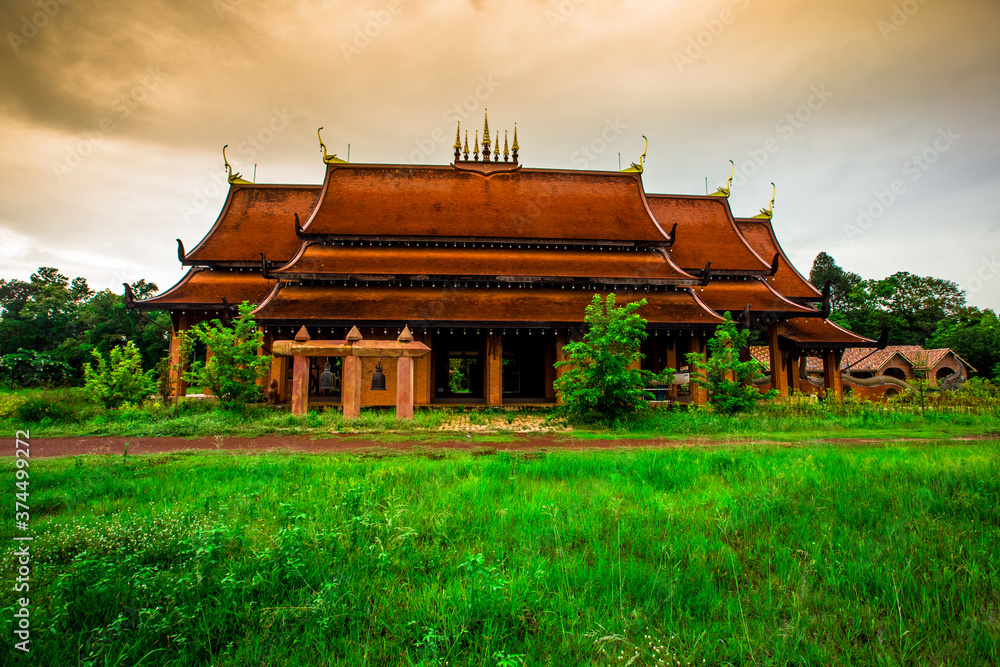 Obraz premium The background of the Wat Pa Kham Charoen is a beautiful old church with a Buddhist statue and a tree-lined temple, with tourists and travelers always making merit in Udon Thani, Thailand.