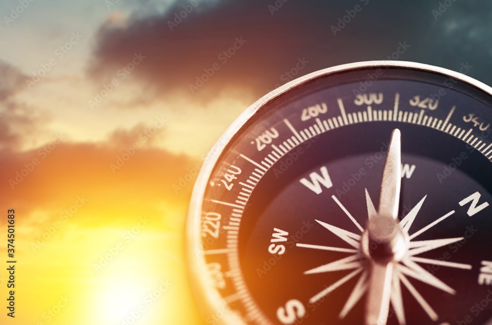 Brass antique classical compass on sunset background Brass antique classical compass on sunset background