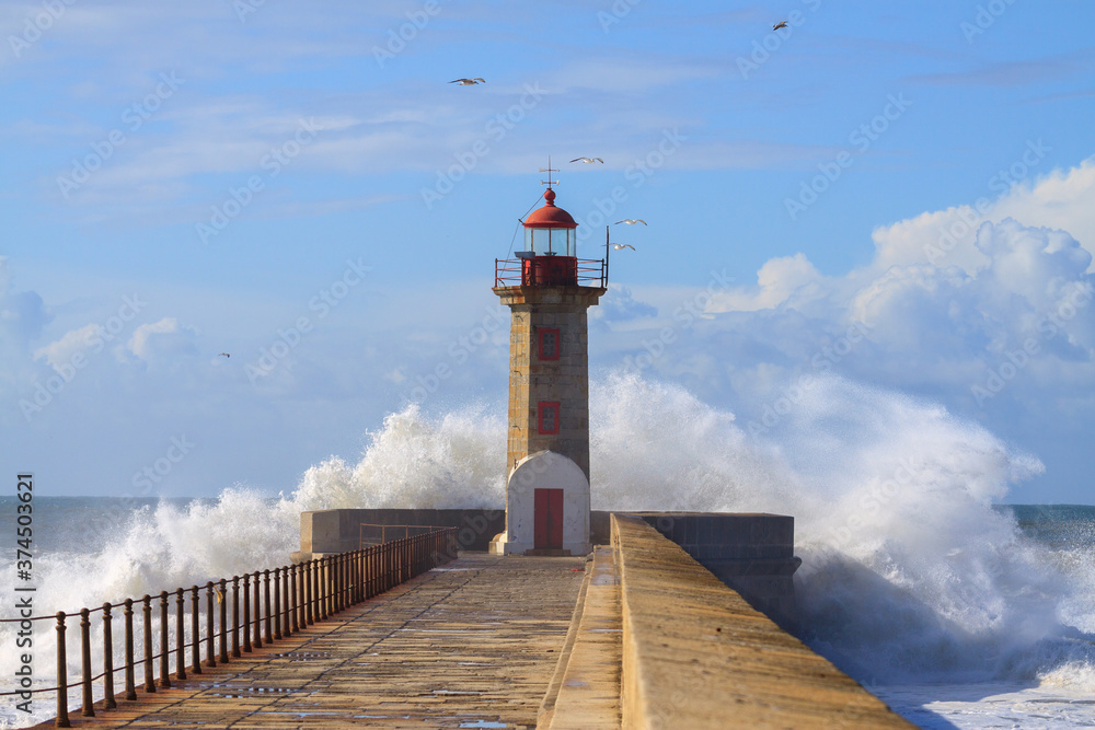 Seascape with big wave crashes at the lighthouse. Maritime landscape. Porto landmark, Portugal. Storm on the stone jetty with very rough sea.