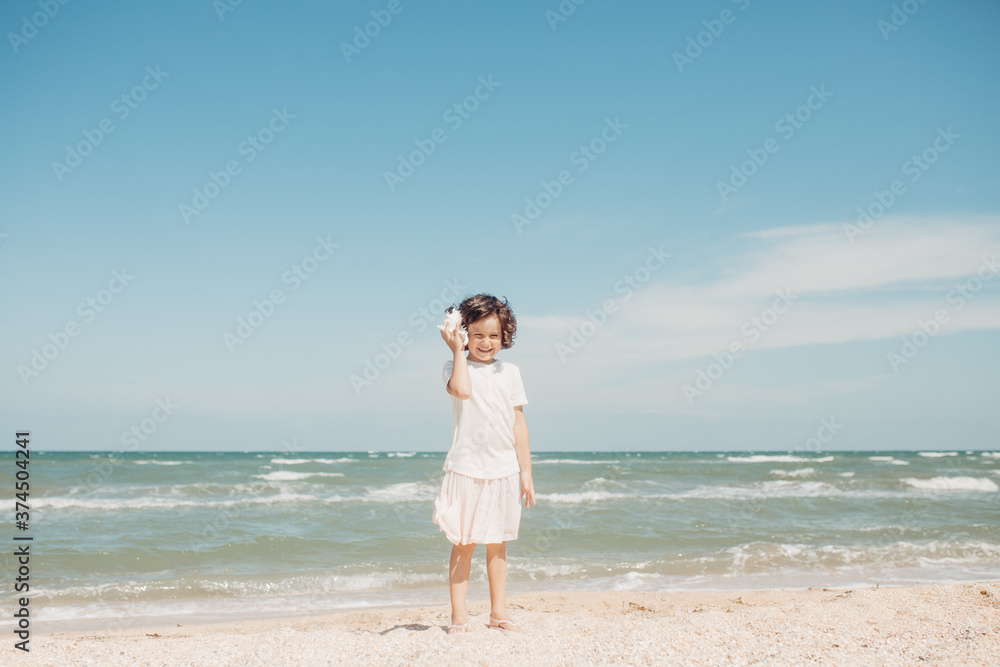 Curly young toddler girl with seashell