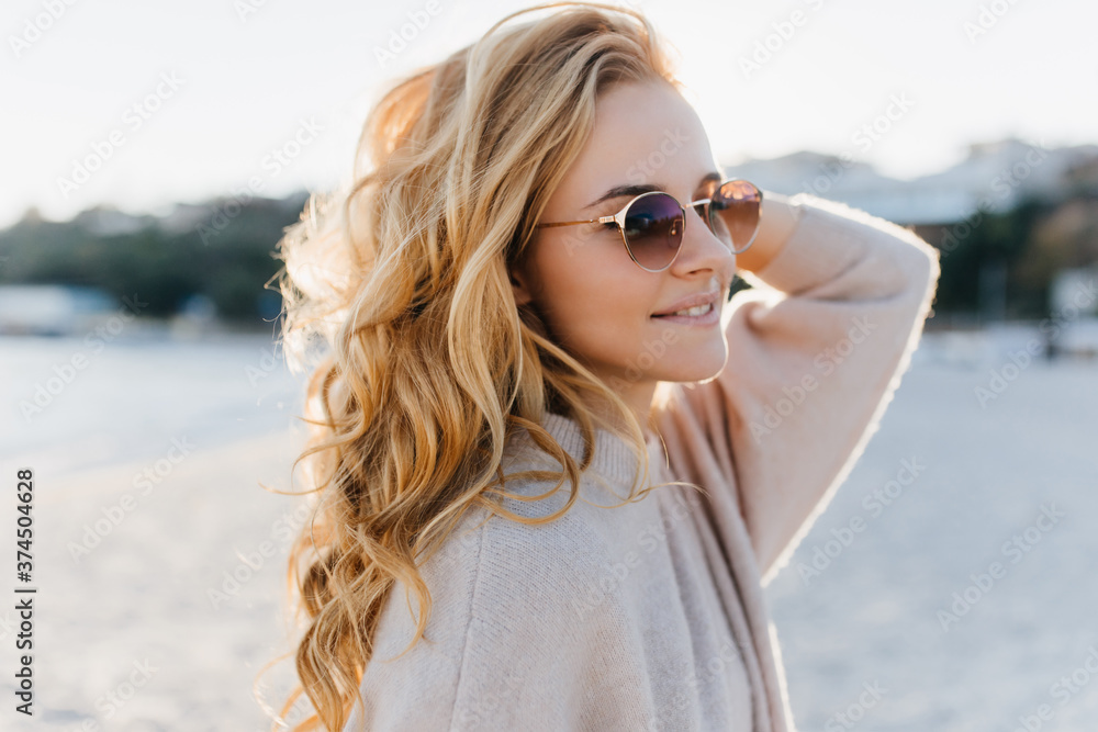 Close-up portrait of young girl without make-up posing on beach in cashmere sweater and glasses Close-up portrait of young girl without make-up posing on beach in cashmere sweater and glasses