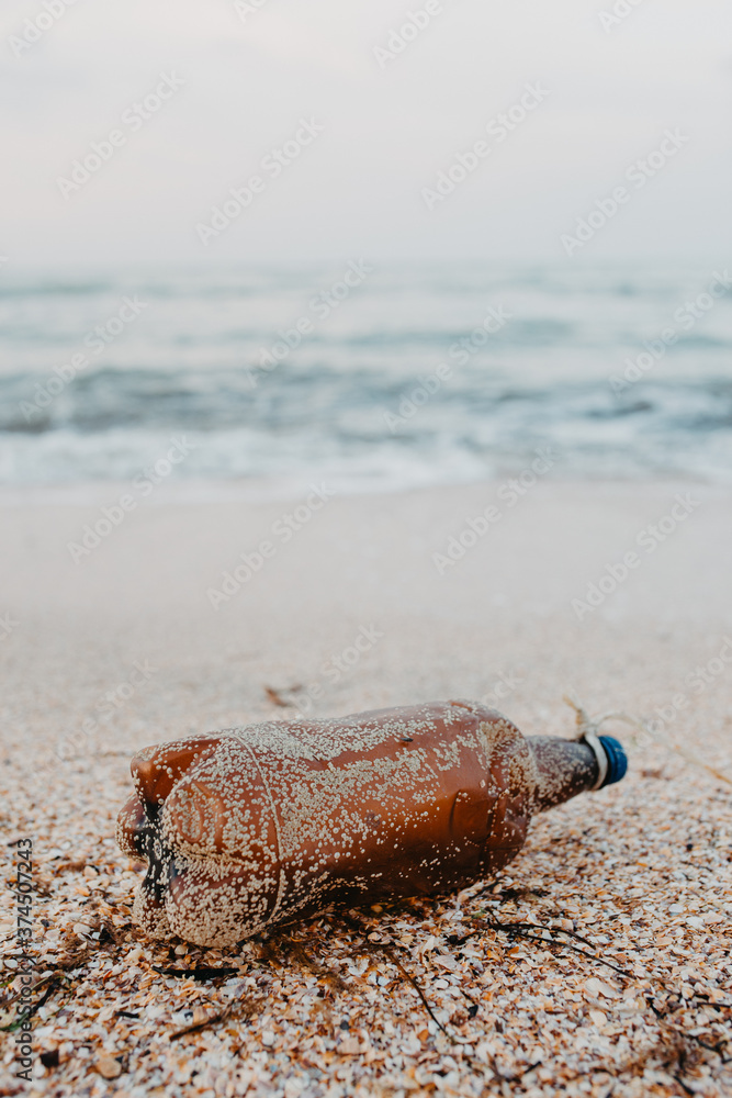 Discarded plastic pet bottle lying on the shoreline causing environmental plastic pollution , Garbage on the beach Discarded plastic pet bottle lying on the shoreline causing environmental plastic pollution , Garbage on the beach