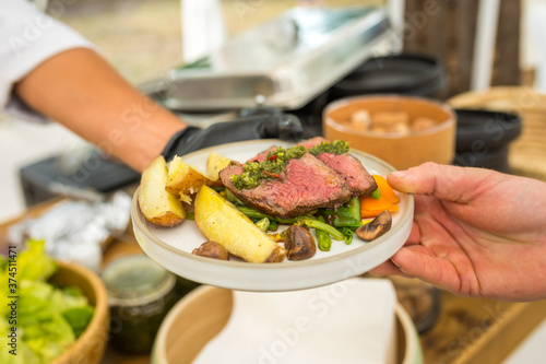 Lamb chops with potatoes and vegetables being served to a guest at an event on a plate - plate of luxury meat at a high class event 