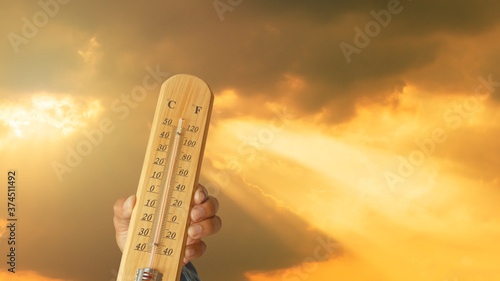 Heat wave background, glowing sun on orange sky with thermometer global warming.
