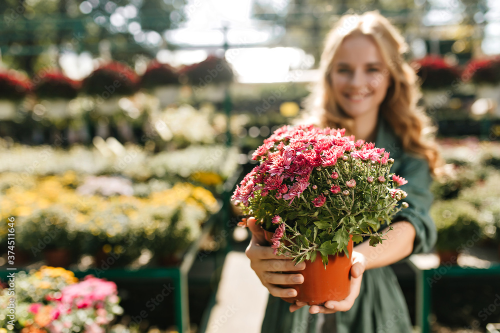 Lovely girl in green dress holding flowers. Blur portrait of smiling lady enjoying gardening in weekend Lovely girl in green dress holding flowers. Blur portrait of smiling lady enjoying gardening in weekend