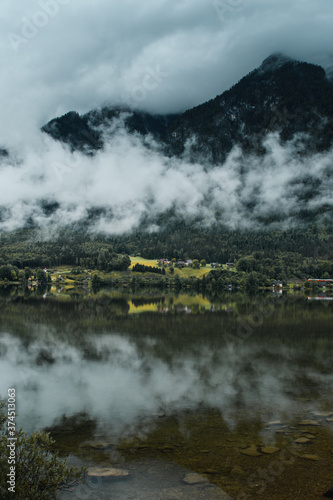 Panorama view of the landscape with a idyllic village located at a lake with mountain background and clouds mist. Hallstätter See, Austrian Alps, Salzkammergut in Austria, Europe