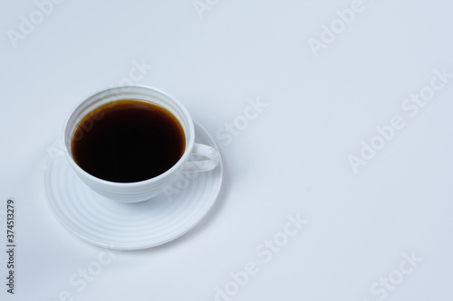 White cup of black coffee isolated on a white background. Top view, copy space.