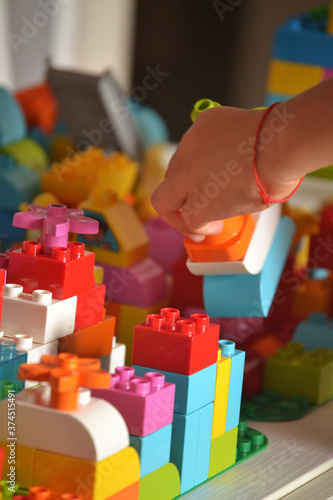 Kid hand detail playing with plastic blocks construction