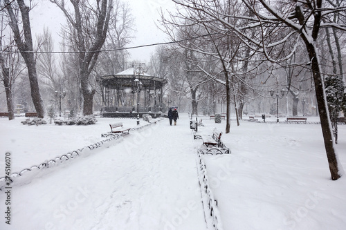 Winter city landscape. People on the streets of the city during snowfall.