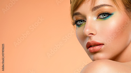 Face of an young girl close-up with a green color makeup. Stylish makeup.