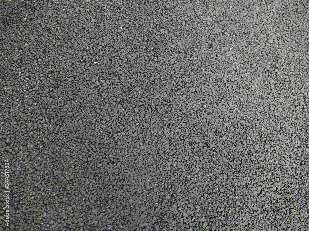 A smooth dark grey asphalt pavement texture with small rocks A smooth dark grey asphalt pavement texture with small rocks