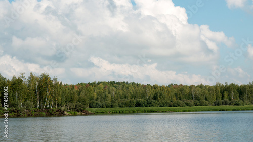 Forest lake view, smooth surface of a lake with clouds reflected, shining level of a forest lake © VP