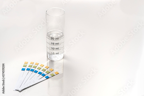 ph test strips with a test tube graduated with water with copy space on the right on a white background photo