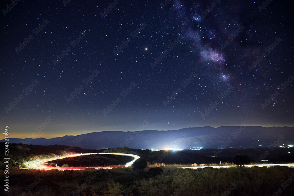 The Milky Way galaxy on a road with lights and a town