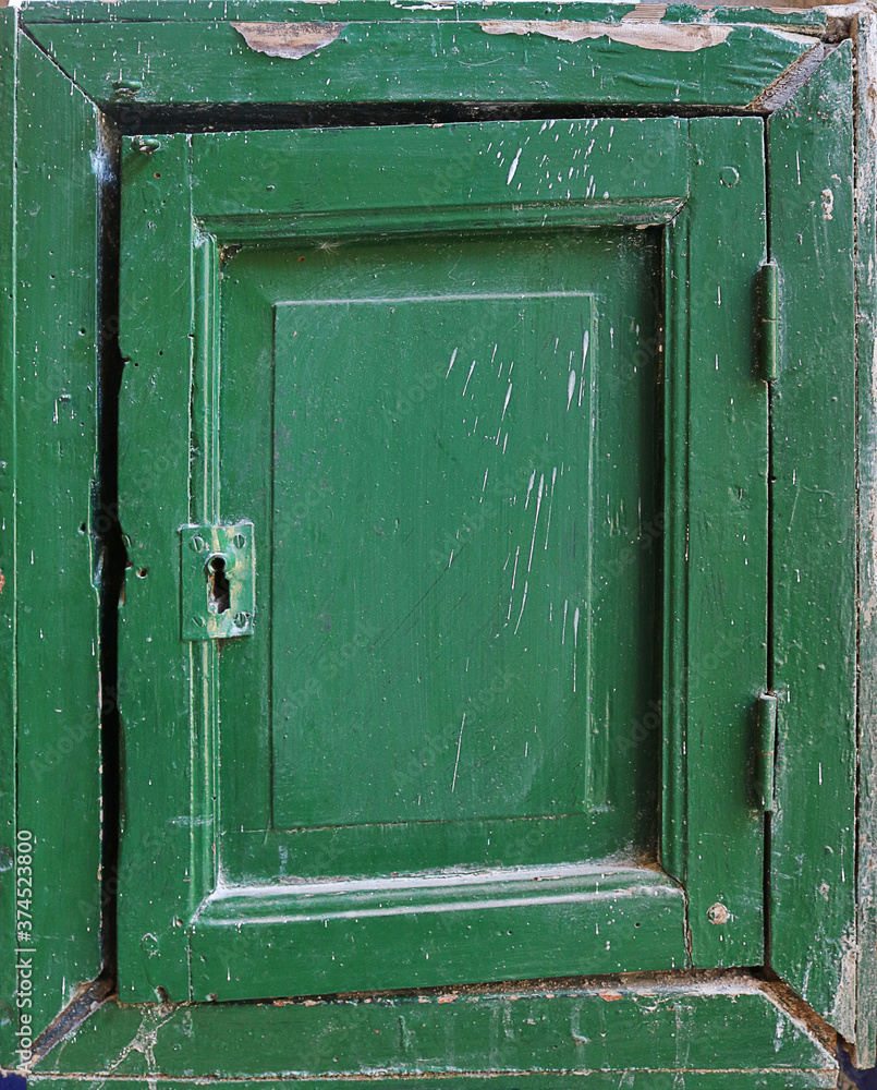 samall old wooden door with square frames of a box, painted in dark green color samall old wooden door with square frames of a box, painted in dark green color