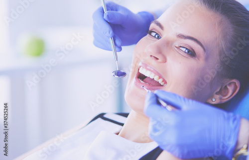 Young Female patient with open mouth examining dental inspection at dentist office.