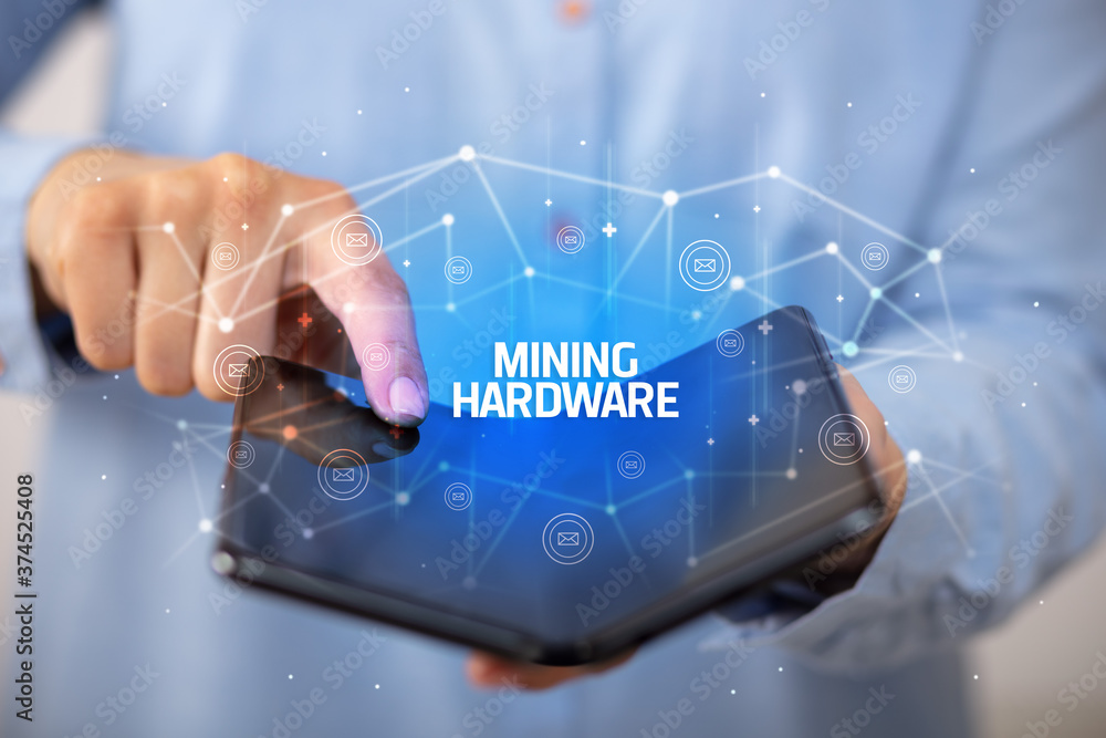 Businessman holding a foldable smartphone with MINING HARDWARE inscription, new technology concept Businessman holding a foldable smartphone with MINING HARDWARE inscription, new technology concept