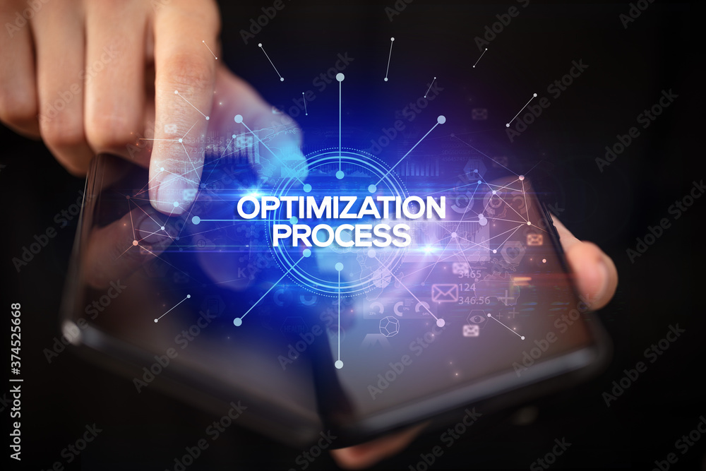Businessman holding a foldable smartphone with OPTIMIZATION PROCESS inscription, new business concept Businessman holding a foldable smartphone with OPTIMIZATION PROCESS inscription, new business concept