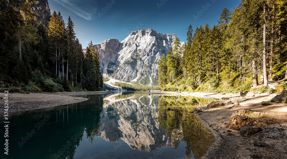 Fototapeta premium Sunny morning at Famouse Mountain Lake in dolomites Alps. Wonderful Braies Lake during sunrise. Amazing Summer Mountain Landscape. Lago di Braies in Spring, Awesome nature Scenery. Pragser wildsee