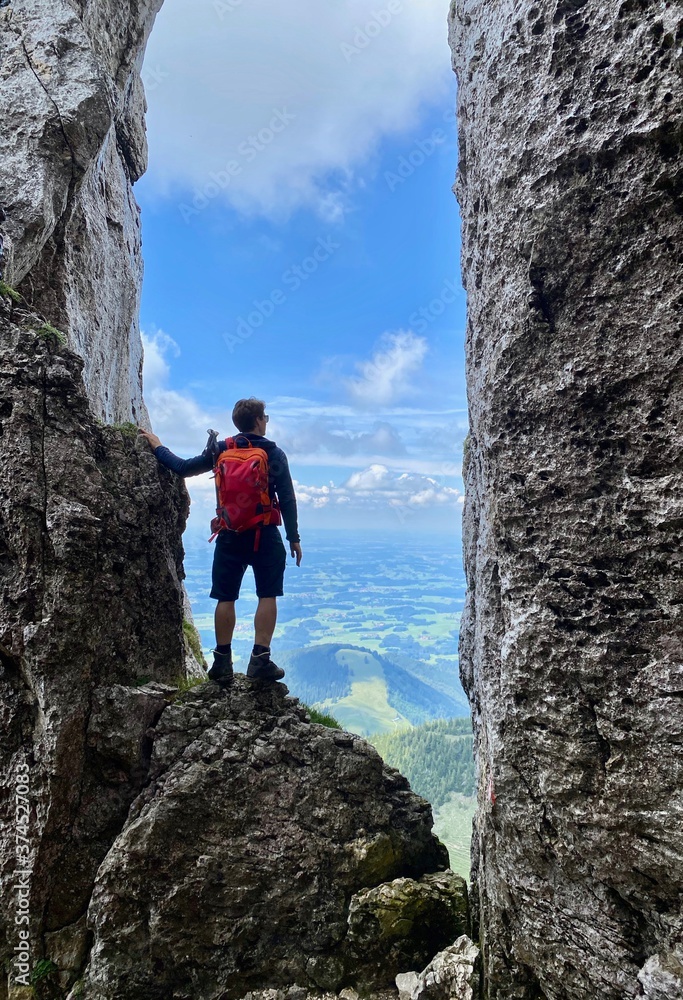 Man standing in stone window, mountain view, blue sky, Bavaria, Germany Man standing in stone window, mountain view, blue sky, Bavaria, Germany