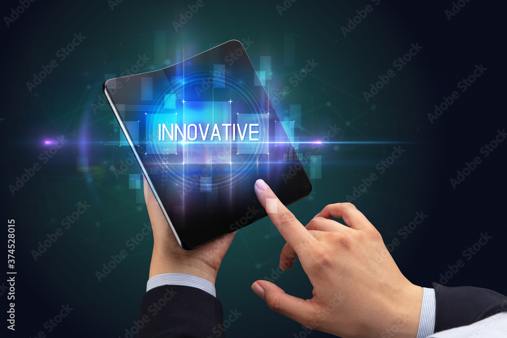 Obraz premium Businessman holding a foldable smartphone with INNOVATIVE inscription, new technology concept