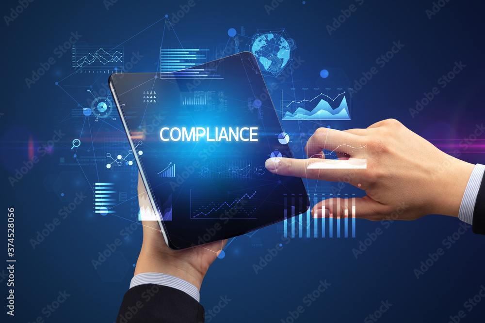 Businessman holding a foldable smartphone with COMPLIANCE inscription, successful business concept Businessman holding a foldable smartphone with COMPLIANCE inscription, successful business concept