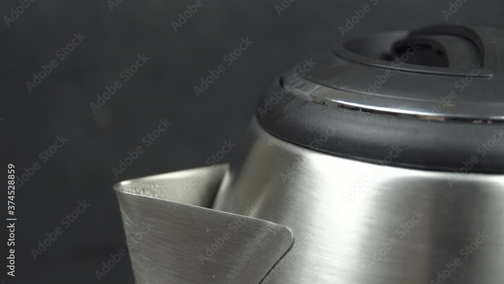 boiling water in an electric kettle, steam escapes from the spout of