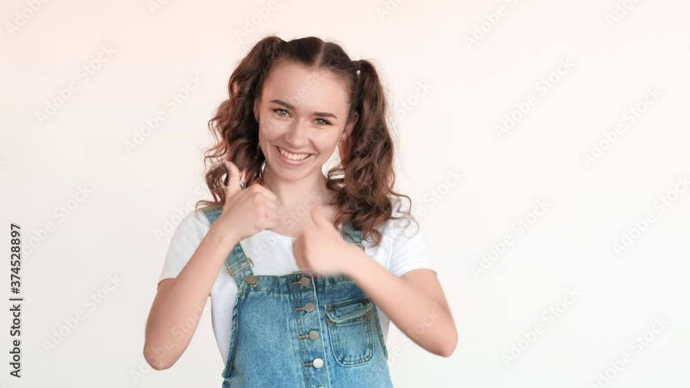 Like gesture. Perfect choice. Amused excited teen girl showing thumbs up smiling isolated on white background. Congrats sign. Admiration support. Super idea. Yes signal. Like gesture. Perfect choice. Amused excited teen girl showing thumbs up smiling isolated on white background. Congrats sign. Admiration support. Super idea. Yes signal.